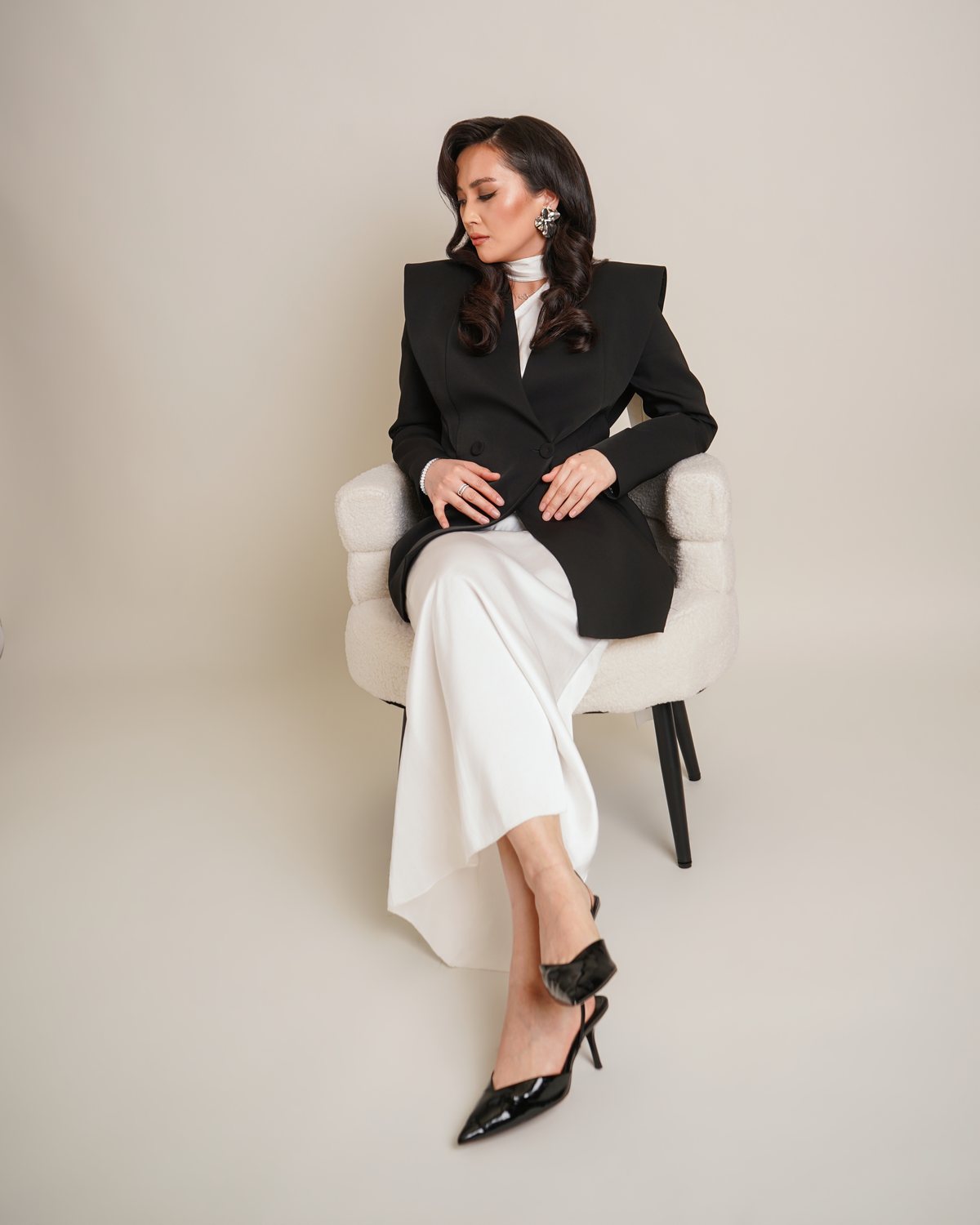 Nurkyz seated in a black blazer and white dress